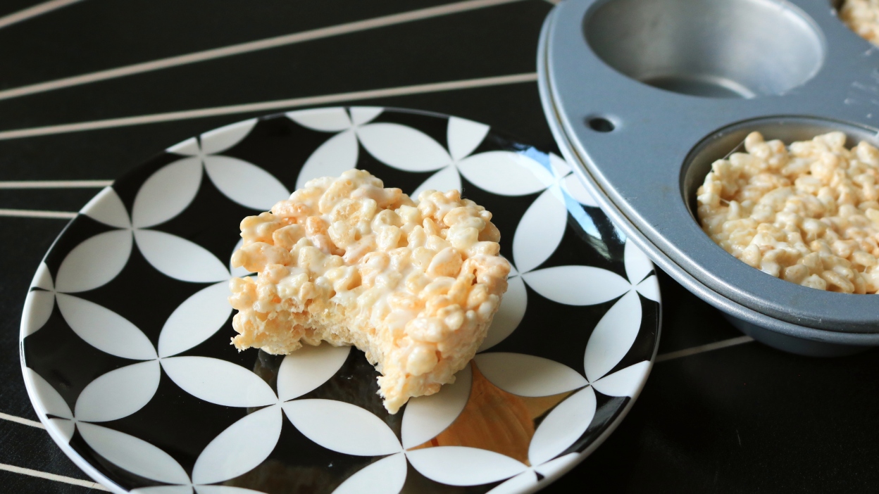 Round rice krispies treat on a black and white plate.