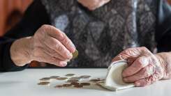 Elderly person counting out small pile of change