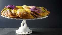 A colorful king cake on a cake stand.