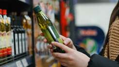 woman holding a bottle of olive oil in a grocery store