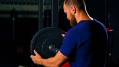 man loading a barbell in a gym
