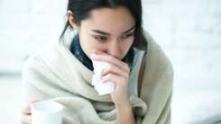 A sick, exhausted woman wrapped in a blanket looking tired