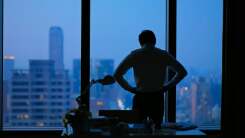 Silhouette of man looking out office window at twilight 