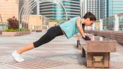 Woman doing push-up on a bench outside 