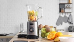 A blender loaded with fruit on a table.