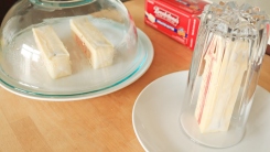 Two sticks of butter underneath a glass bowl and a stick of butter under a glass cup.