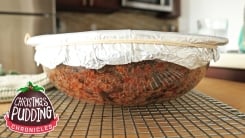 A cake inside of a glass bowl topped with foil