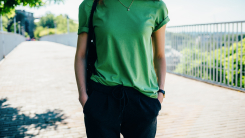Young woman in a green t-shirt and black pants on the street in summer