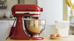 A red stand mixer sits on a countertop.