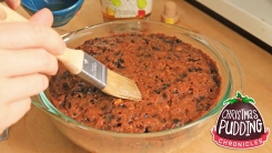 Hand brushing top of cake with pastry brush.