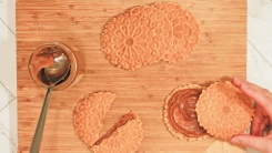 Pizzelles on a cutting board with a jar of dulce de leche.