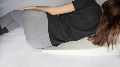 Woman lies on wedge pillow 
