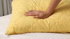 Woman putting hand on yellow pillow 