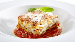 A slice of lasagna in a white bowl.
