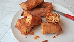 A pile of lasagna and chicken dip egg rolls on a plate with two cut in half