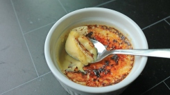 Crème brûlée with a spoon scooping a bit.