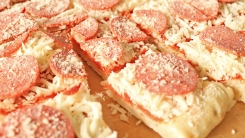 A frozen pizza cut into small slices up-close.
