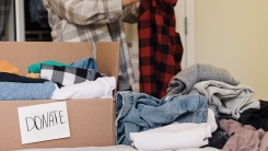 person sorting clothes and putting some into "donate" box