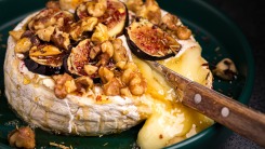 Close-up of melted brie cheese topped with walnuts and figs.