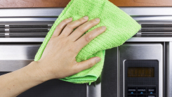 hand cleaning microwave with green cloth