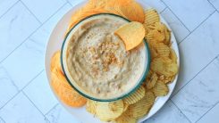 Onion dip in a bowl with chips around it on a plate