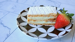 A slice of mille-feuille on a plate with a strawberry