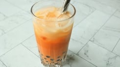 Thai boba milk tea in a glass with a silver straw.