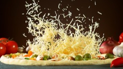 Shredded mozzarella cheese falling onto a pizza