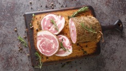 Pancetta on a cutting board with rosemary.