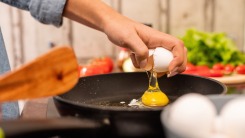 Hand cracking an egg into a skillet