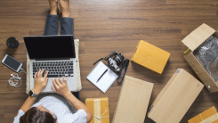 person with laptop surrounded by boxes