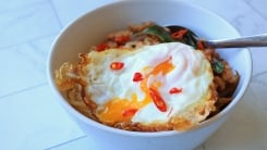 A bowl of noodles and a fried egg on top.