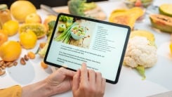 Hands scrolling a recipe on a tablet.