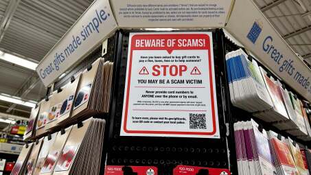 "Beware of scams" sign hanging near gift cards for sale