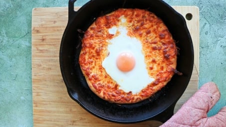 A pizza in a cast iron skillet.