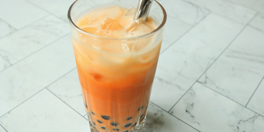 Thai boba milk tea in a glass with a silver straw.