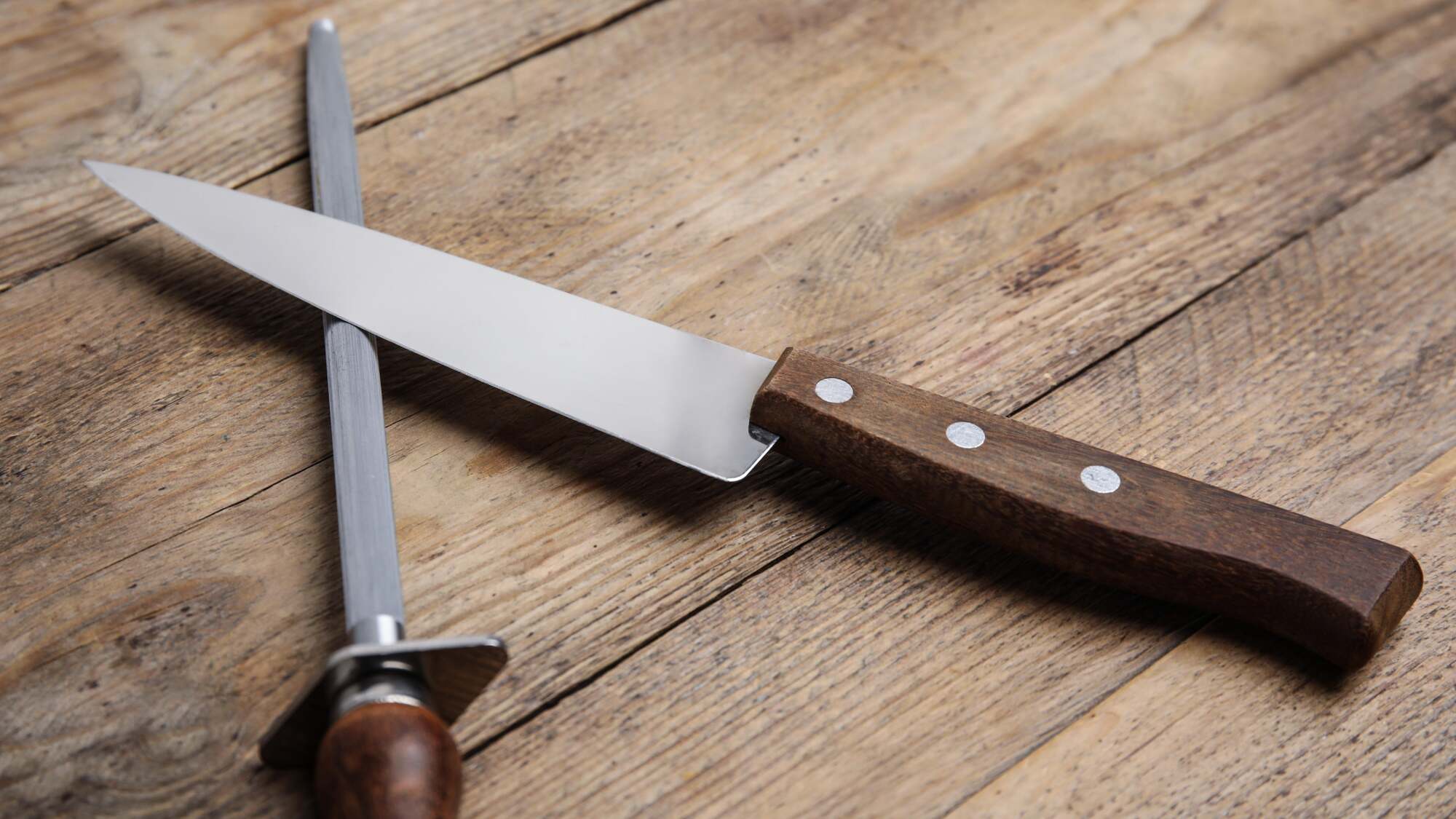 A knife and honing steel sit on a table.