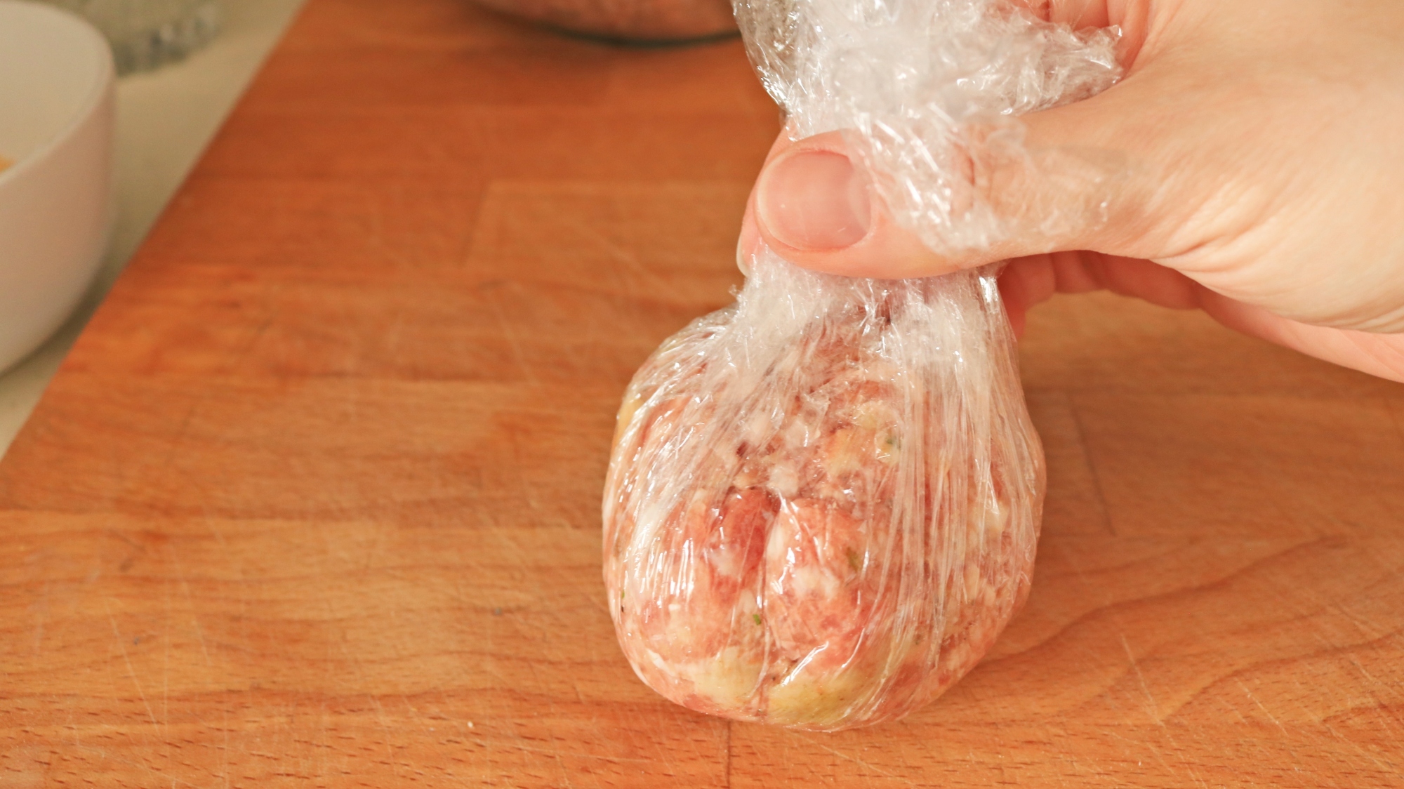 Plastic wrap with a ball of sausage inside