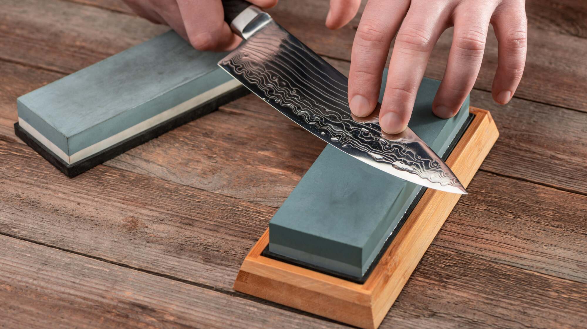A person sharpening a knife on a whetstone.