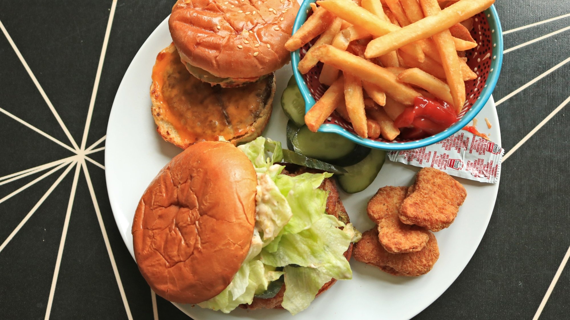 Burgers and fries on a plate with chicken nuggets and fries.