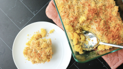 Mac and cheese casserole with a scoop on a plate nearby.