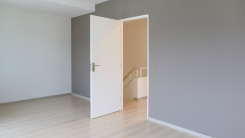 A painted gray wall with an open door leading to a stairwell