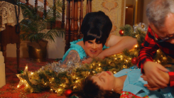 A screenshot from Female Trouble of Devine crouching over a fallen Christmas tree