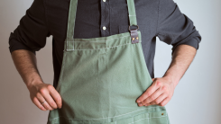 A person putting on a green apron