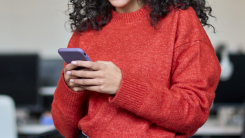 A person wearing a red sweater looking at their phone