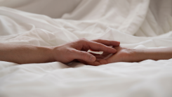 Two hands holding in a tangle of bedsheets