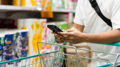 Person typing into smartphone in grocery store aisle
