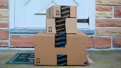 Three Amazon Prime packages stacked on the front porch of a home