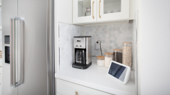 A kitchen with smart appliances including a fridge, coffee maker, and tablet