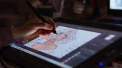 An artist using a stylus to create a digital drawing of a woman on a tablet
